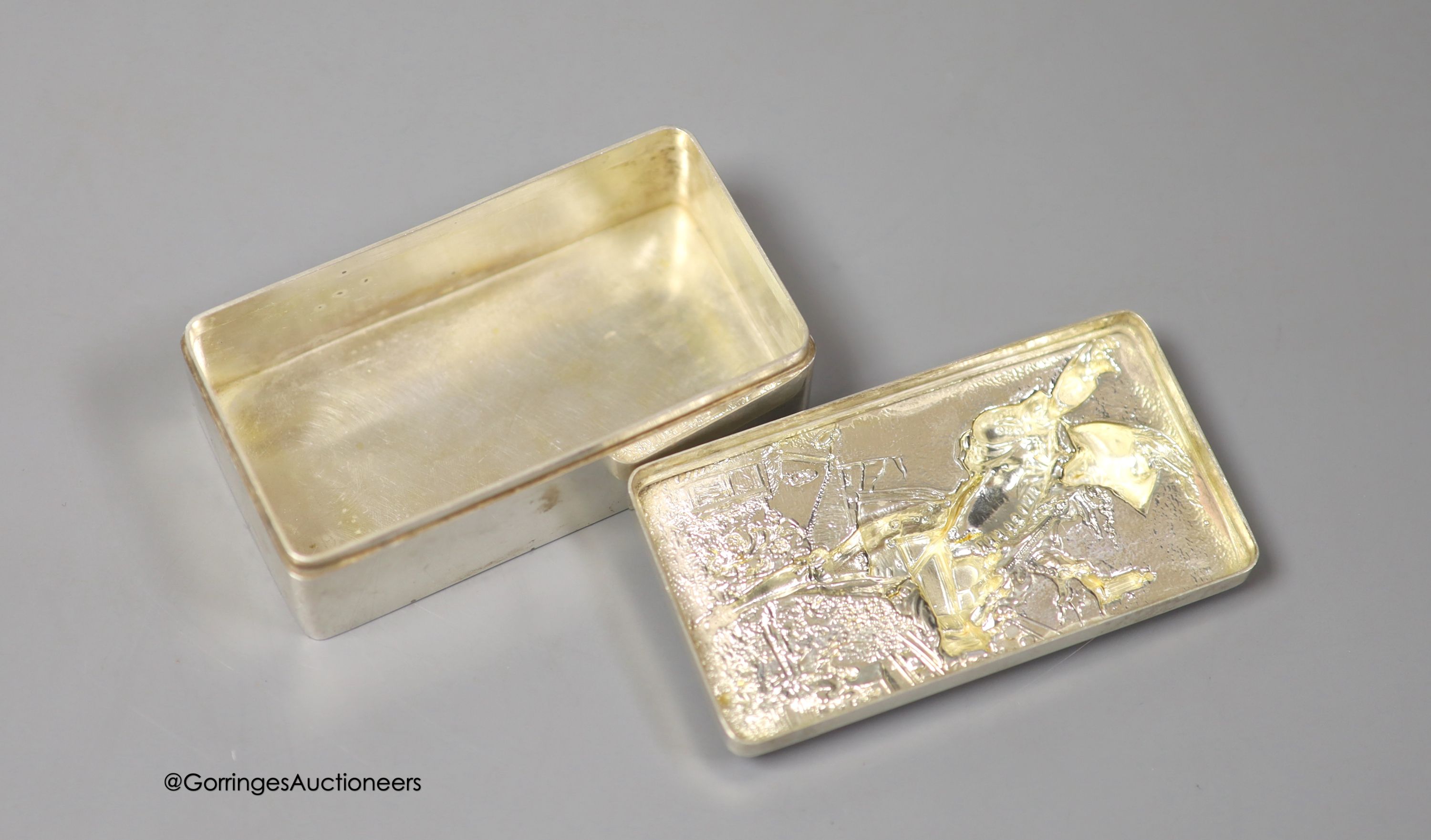A late 19th/early 20th century continental white metal rectangular box and cover, the lid embossed with the figure of a pedlar, 9.5cm, 155 grams.
